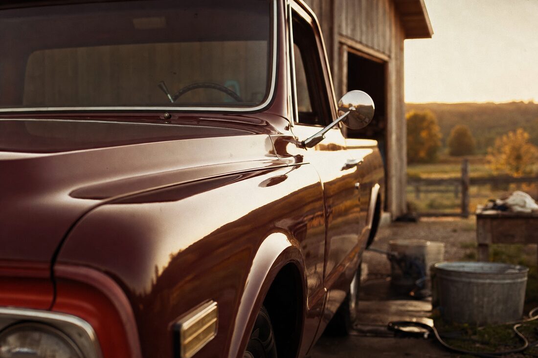 A freshly detailed pickup truck gleaming in golden-hour light outside a rural shop